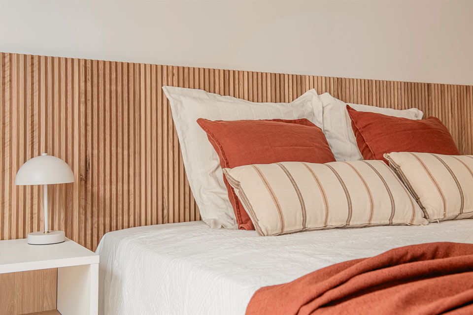 Dormitorio con mobiliario a medida. Cabecero de madera de roble natural con acanaladura vertical y mesillas y cómodas a juego.