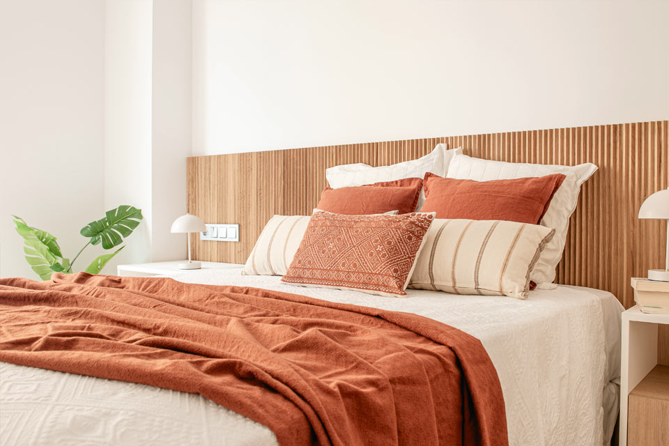 Dormitorio con mobiliario a medida. Cabecero de madera de roble natural con acanaladura vertical y mesillas y cómodas a juego.